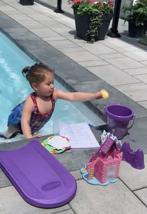 Une jeune fille joue dans l'eau avec des jouets aquatique