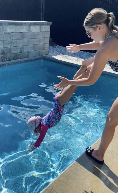 Une monitrice aquatique donne un cours de natation à domicile à une élève dans un piscine creusée